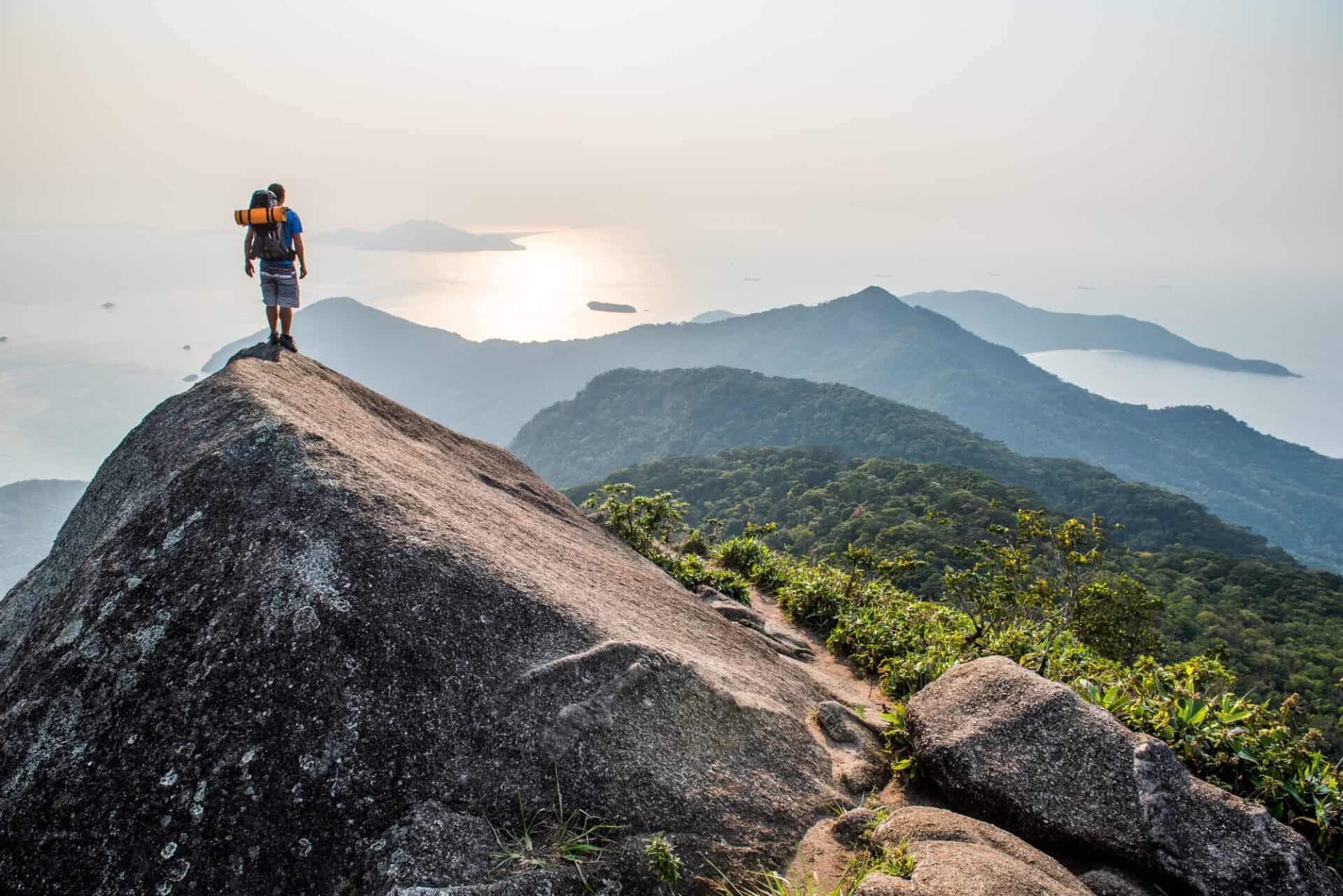 Hiker on top of mountain with ocean view, Pico Do Papagaio, Costa Verde, Brazil