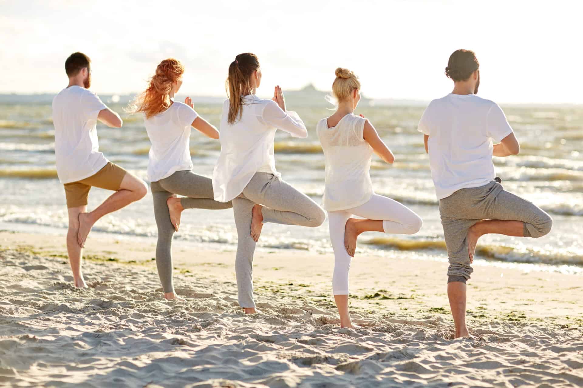 yoga, group of people in tree pose on beach